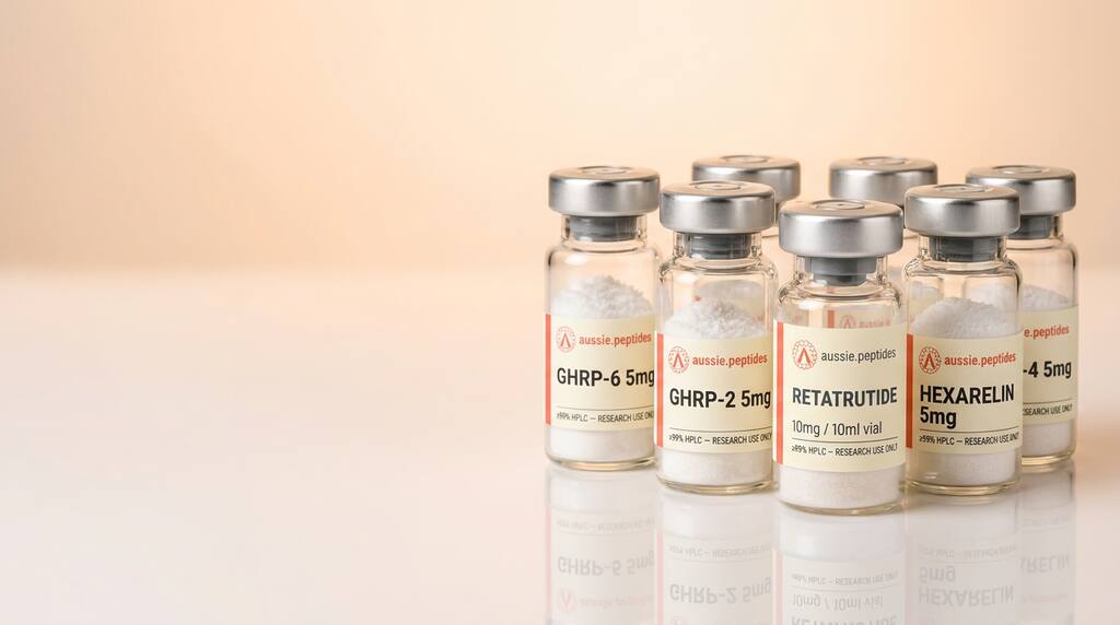 Row of Aussie Peptides branded glass vials with silver crimp caps and cream labels on a reflective studio surface